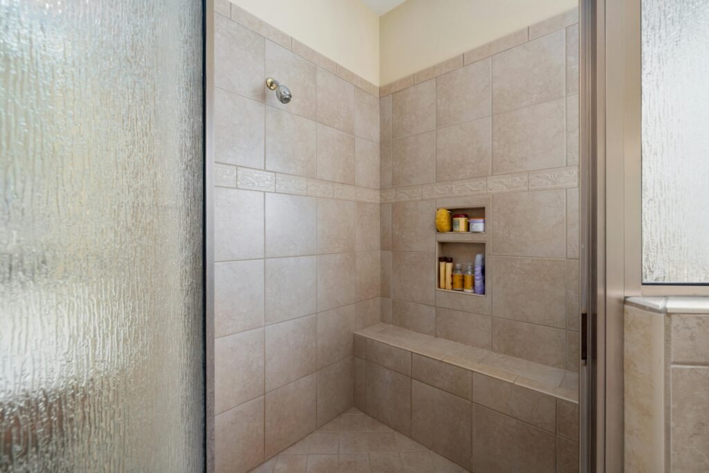 Elegant walk-in shower with beige tiles and built-in shelves, perfect for a modern bathroom.